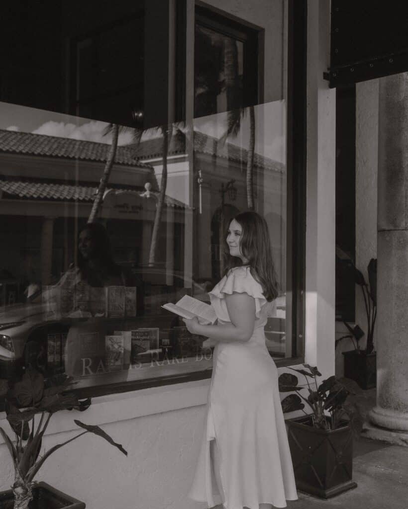 Young woman reading a book outside a bookstore for Wandering Lights Literary Magazine.